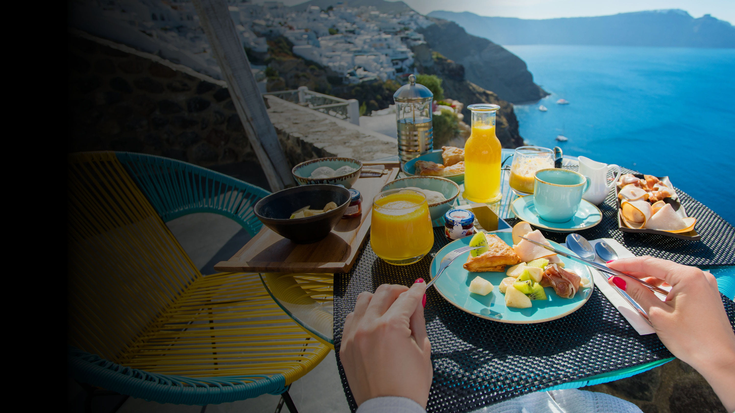 A person sitting at a table outside eating by the ocean