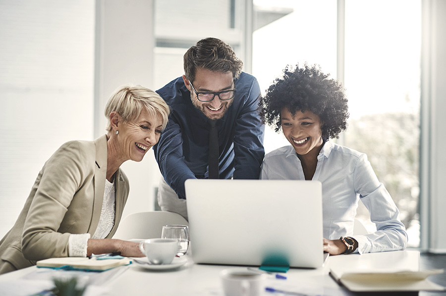 A man and two women looking at a laptop screen
