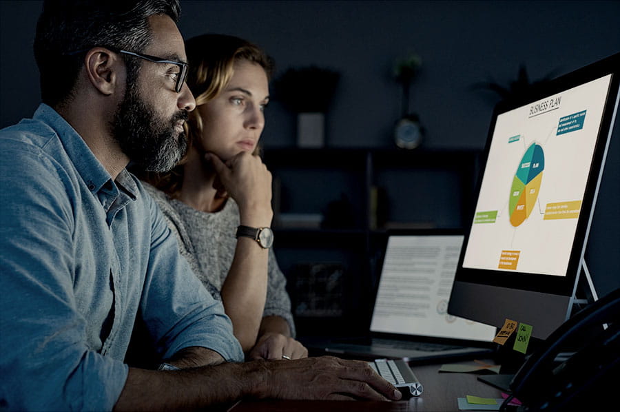 Two people looking at data on a computer.