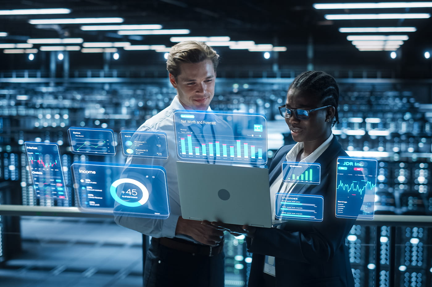 A man and woman in a tech room holding a tablet device with technical visuals on the screen next to the tablet. 