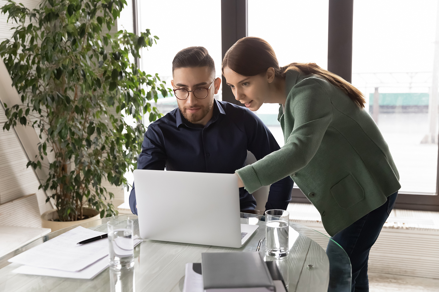 Two colleagues looking at something on a laptop together.