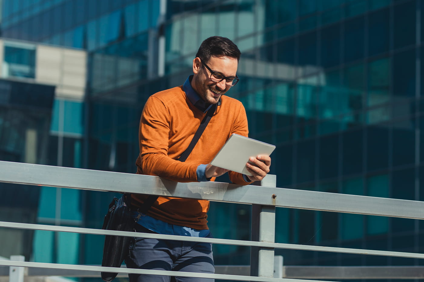 A man looking at a tablet outside of a large building.