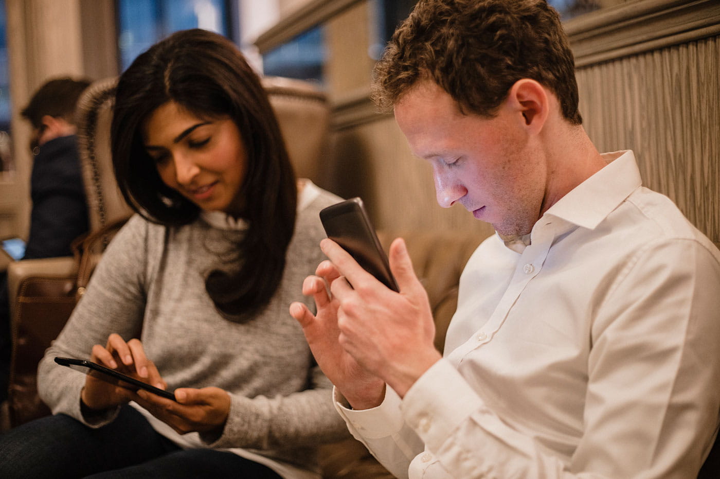 A man and woman working on their cellphones.
