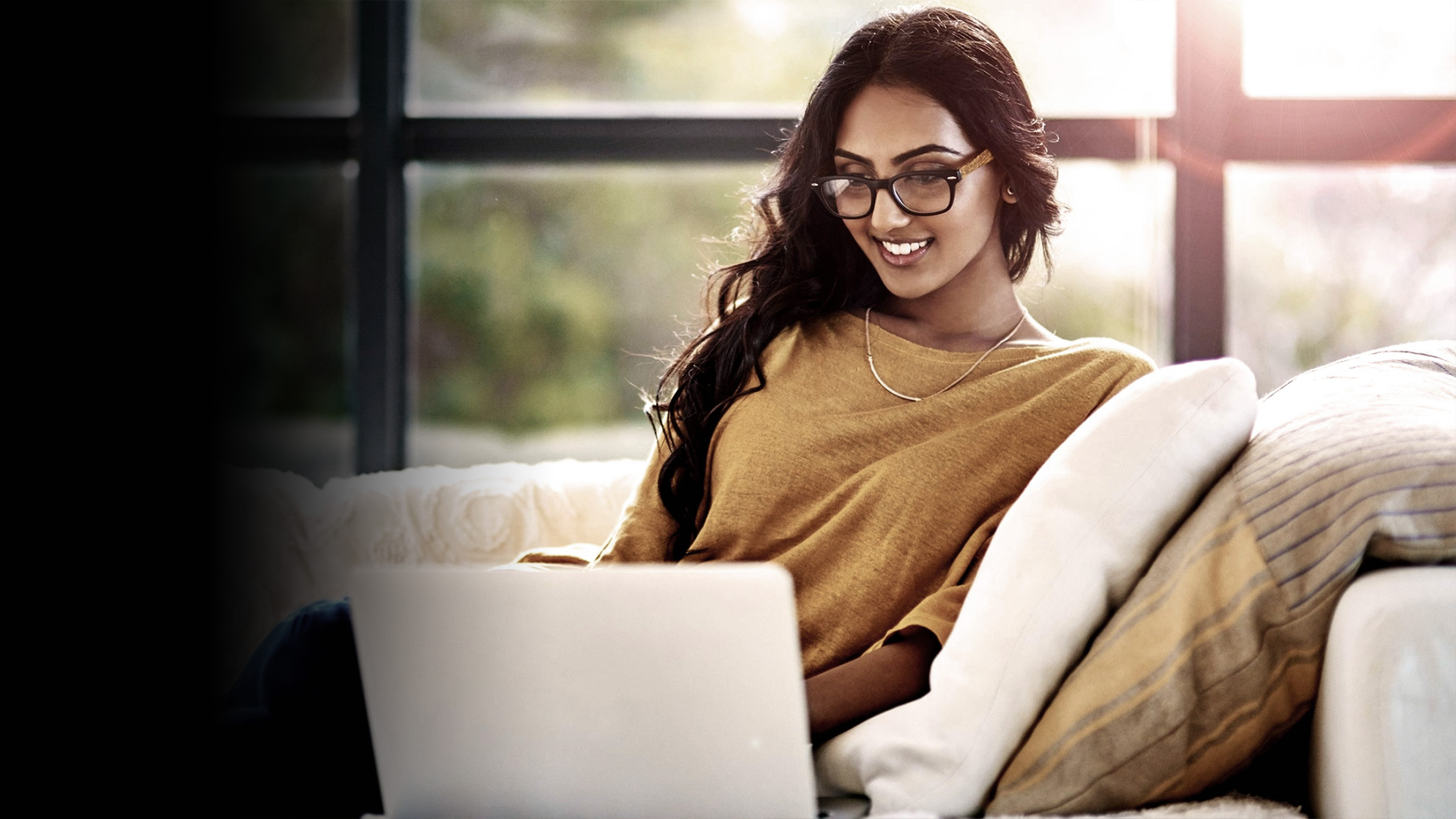 A woman sitting on her couch and working on her laptop.