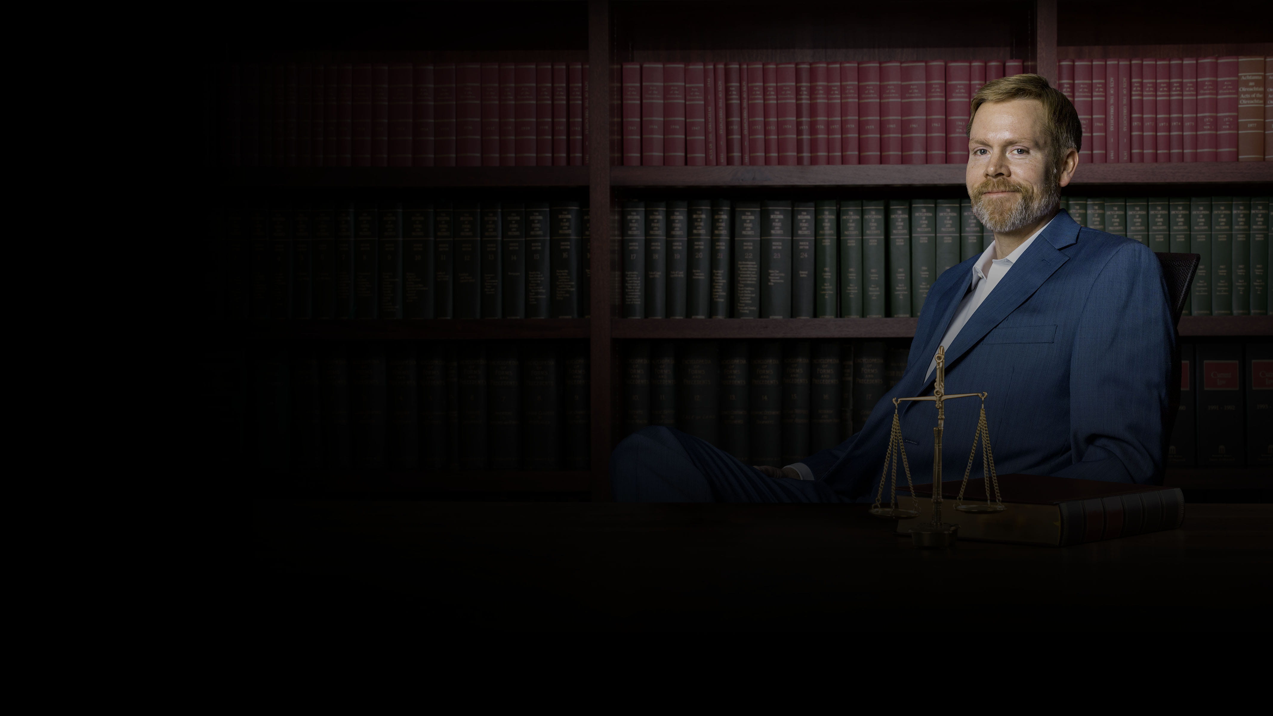 Cameron Walbert sitting in front of a bookcase.