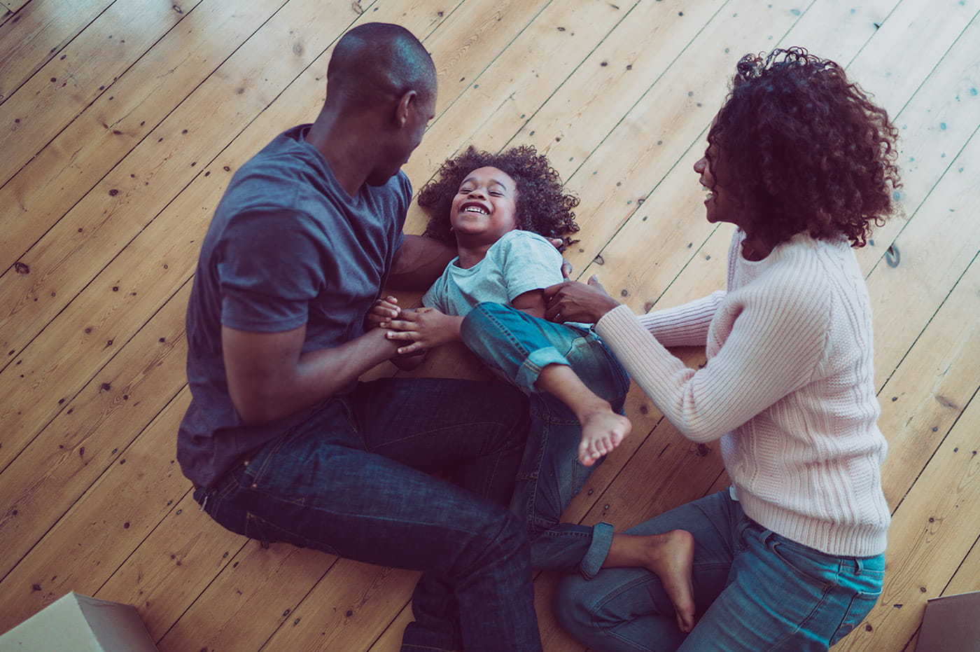 A family playing on the floor with their young child.