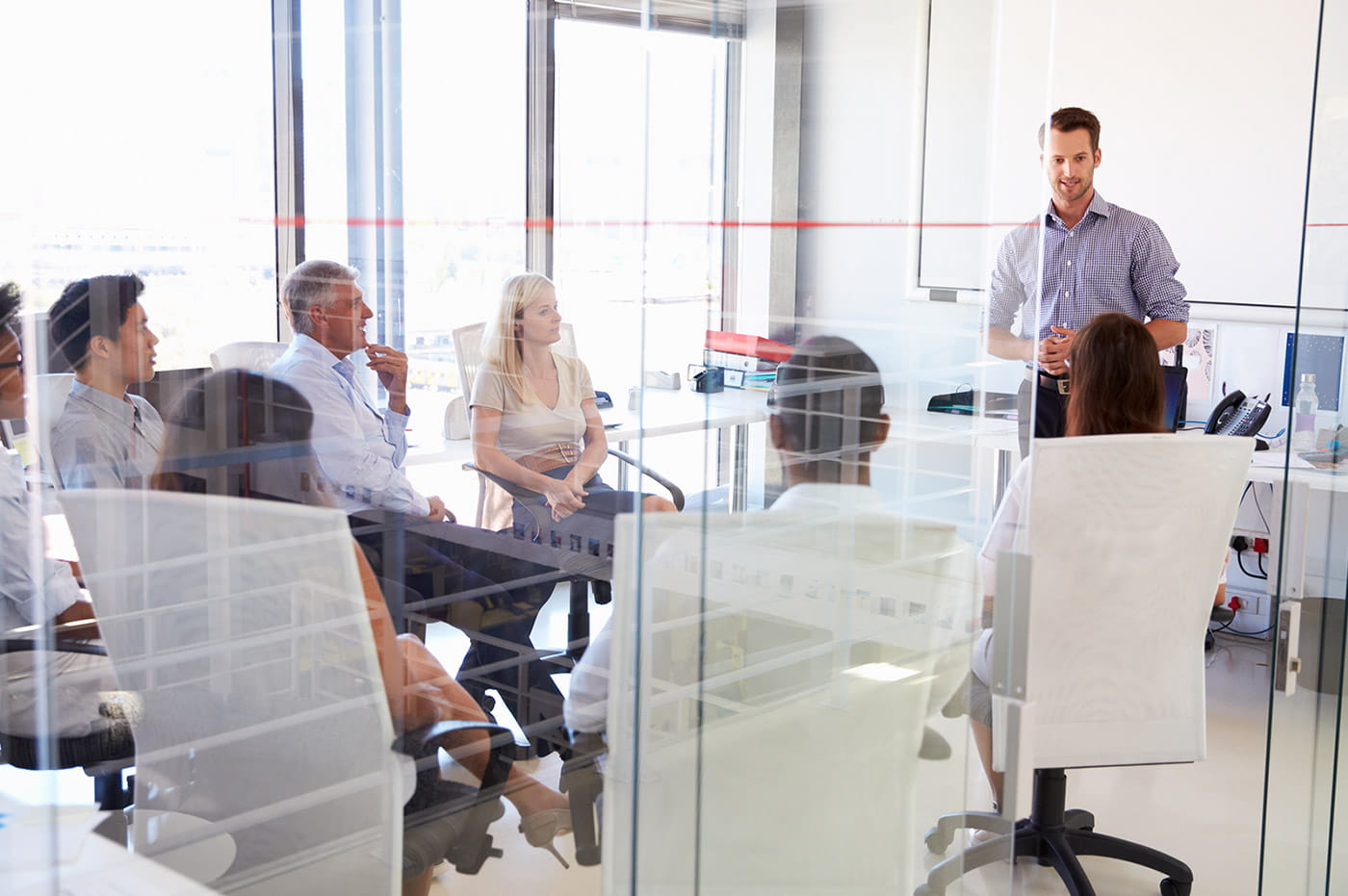 People sitting in a circle listening to a man standing and talking.