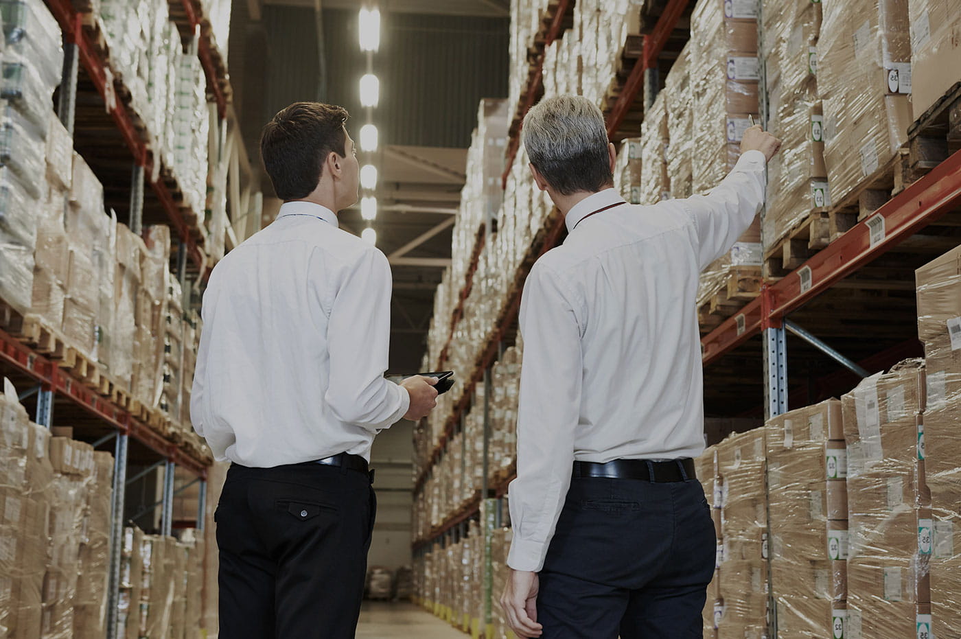 Two men standing and talking in a large warehouse.